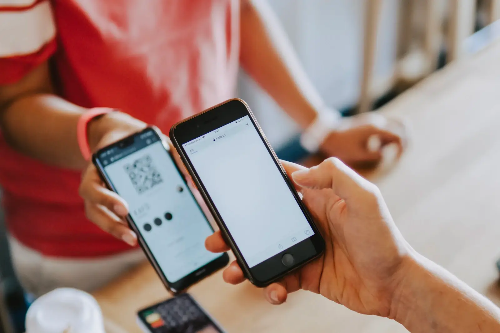 Покупатель сканирует своим смартфоном QR-код с экрана второго телефона на кассе