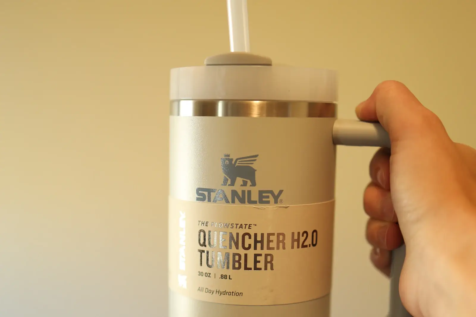 Рука держит термокружку Stanley Quencher с трубочкой